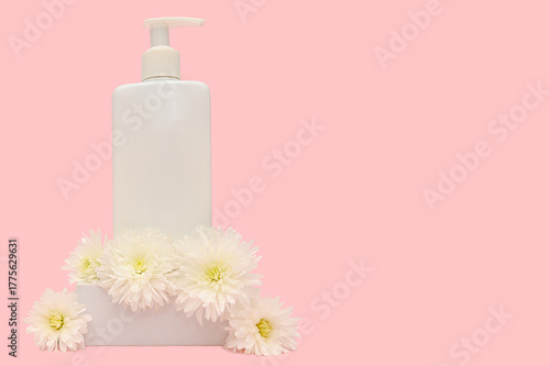 White container with dispenser on pink background with white flowers.
