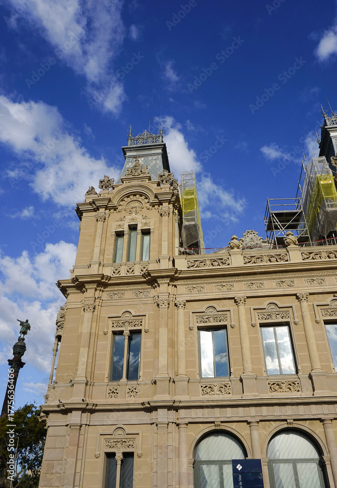 Obraz premium Aduana Building or Duana Nova New Customs House at Gate of Peace Port Vell in Barcelona, Spain. Neoclassical design with reliefs of royal crowns, crenels, topped with sculptures of winged lions.