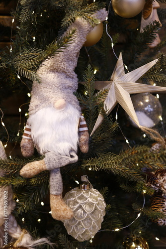 Décoration de noël dans les tons blanc avec un lutin blanc , une étoile blanche et boule de noël blanche suspendues dans un sapin