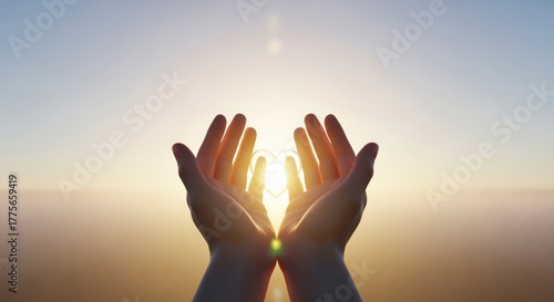 A pair of hands cupping light in a heart shape against a serene sunset backdrop, symbolizing love and hope.