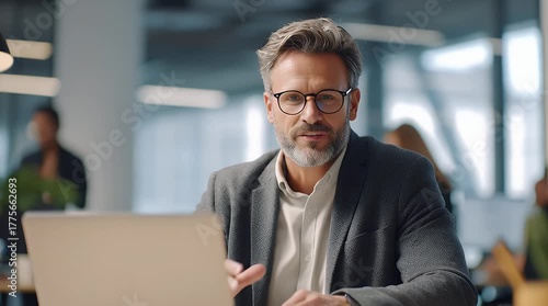 Focused Mature Businessman Working Online Using Laptop at Modern Workplace