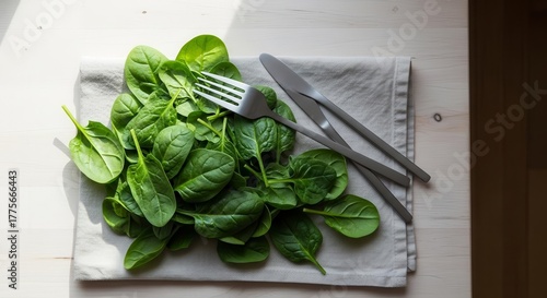 Fresh Spinach Salad with Cutlery on a White Wooden Table for Healthy Eating