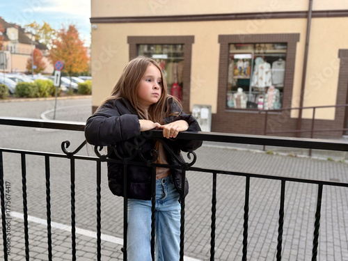 Thoughtful girl leaning on railing in urban setting