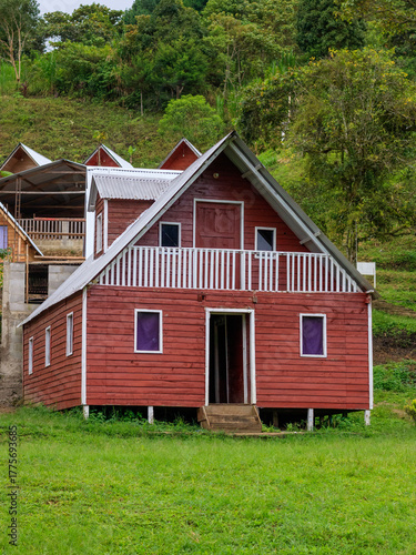 Bright red wooden house set against green hillside in a sunny rural area during the day
