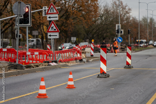 City roadway under repair with visible traffic cones, construction signage, and workers in reflective clothing representing municipal street reconstruction and civil engineering operations