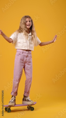 Young blonde girl learning to balance on a skateboard. Vertical