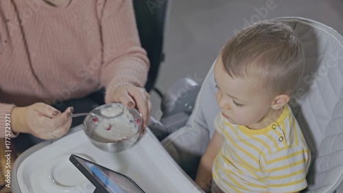 Mother feeding her baby boy in a high chair
