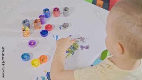 Toddler finger painting with colorful paints on paper
