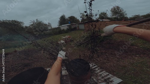 A man burns grass in an iron barrel, burning grass in a barrel, burning grass in a cottage
