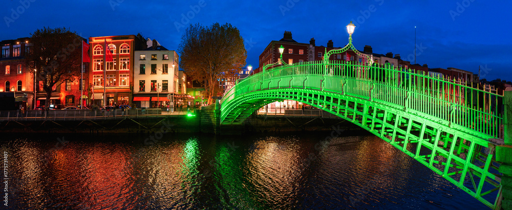Obraz premium Ha'penny Bridge or Droichead na Life, refurbished 19th-century cast-iron span illuminated in green at night over River Liffey, Dublin, Ireland.
