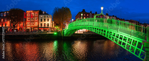 Ha'penny Bridge or Droichead na Life, refurbished 19th-century cast-iron span illuminated in green at night over River Liffey, Dublin, Ireland.
