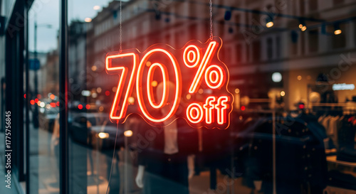 Neon sign advertising a 70% off sale in a shop window at dusk