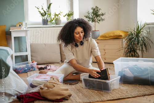 Young woman sorting wardrobe indoors at home, charity donation concept.