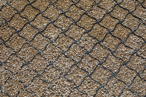 Polymer geogrid reinforcement over gravel surface for soil stabilization. For erosion control, road construction, and permeable pavement systems. Real photo