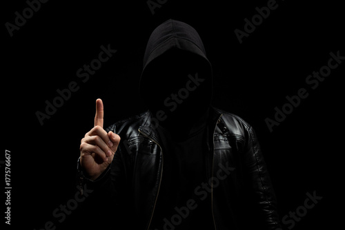 a faceless hooded man in the shadows pointing to the sky with his right hand and a black background
