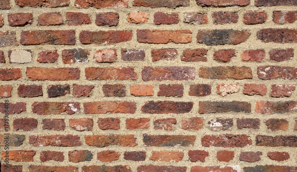 Fototapeta premium Weathered red brick wall with rough surface texture and beige mortar joints, natural rustic construction background pattern