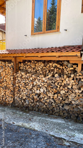 Foto Neatly stacked firewood under wooden shelter against house wall