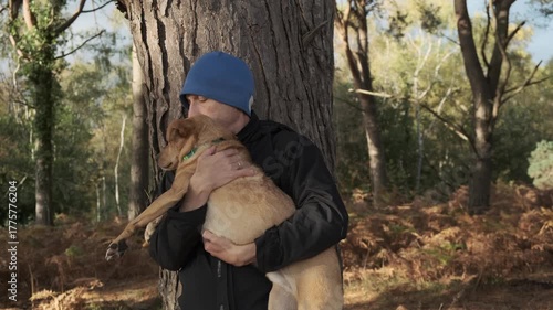 Man holding cuddling a dog close in a beautiful woodland in the evening sun