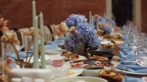 Elegant wedding table decoration with flowers and candles, festive dinner setup with blue napkins and delicious appetizers, luxury event or celebration concept with soft natural lighting