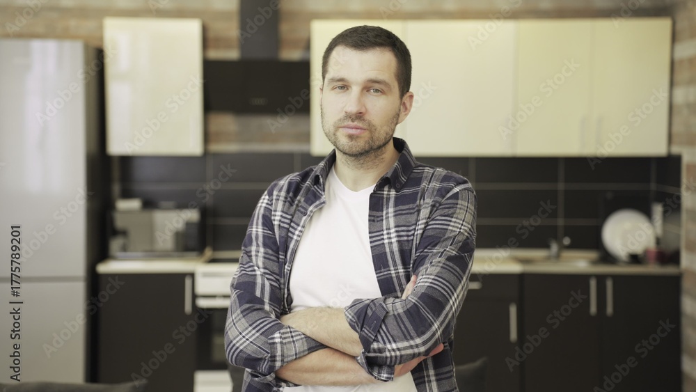 Fototapeta premium Confident man in checkered shirt standing on kitchen, looking at camera