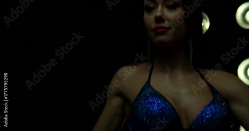 Competitor stands confidently showing defined muscle tone and stage presence. The setting highlights the importance of posing in bikini fitness competitions.