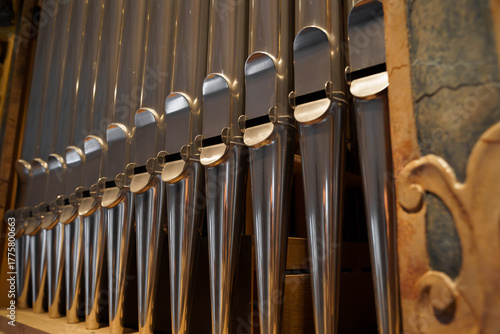Shining organ pipes in warm church light, symbolizing sacred music and craftsmanship; vertical detail with copy space, ideal for worship and concert branding.