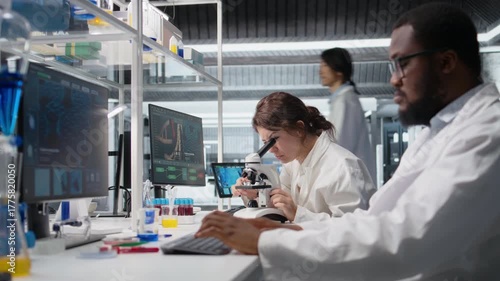 Zoom in on histology technician in lab using scientific microscope for cellular analysis. Woman studies microorganisms inside modern research facility with optical device equipment, camera A