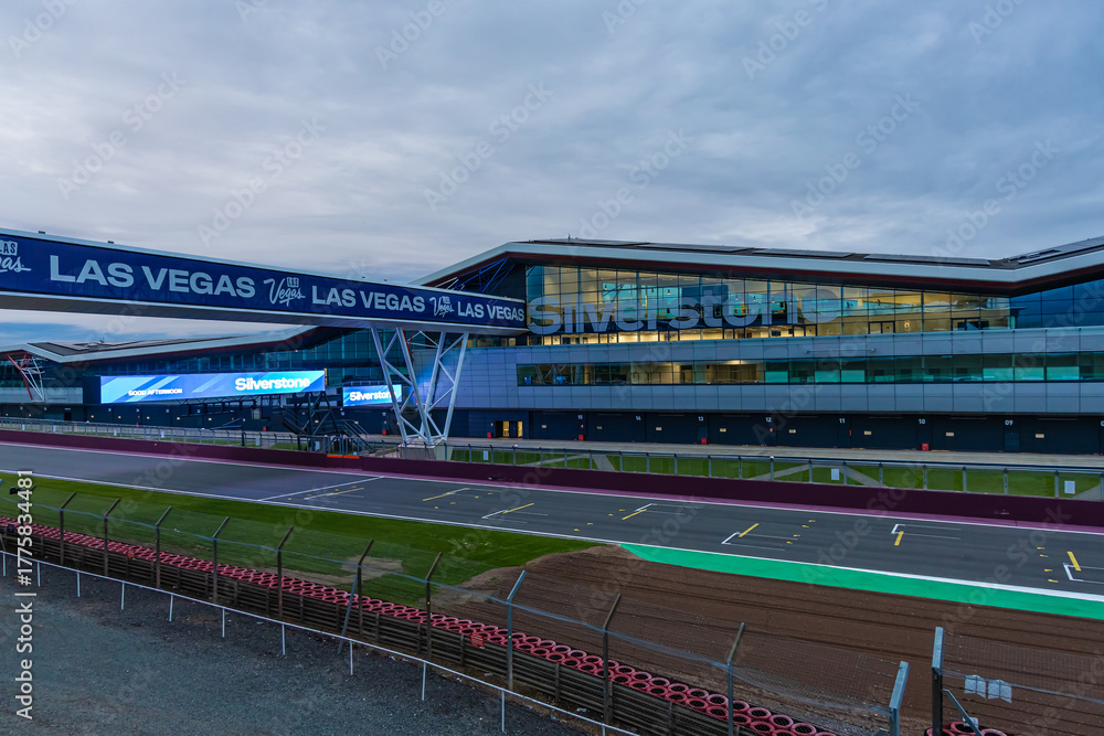 Fototapeta premium The Silverstone pit building lit up at twilight, ideal for motorsport, travel, and architecture themes.