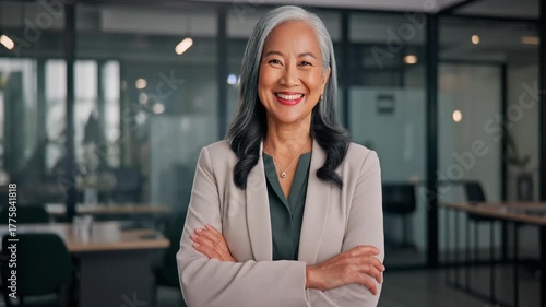 Happy elegant older mature lady posing for portrait standing in office. Beautiful middle aged business woman looking at camera, smiling 45 years old businesswoman leader executive at work.