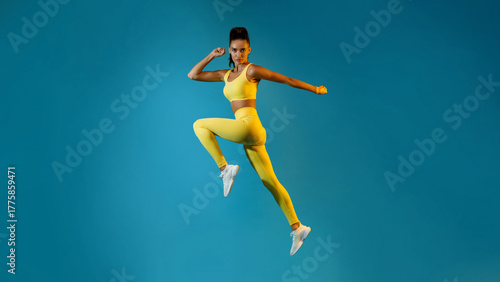 Wallpaper Mural A female athlete leaps into the air, striking a powerful pose while maintaining eye contact with the camera. Torontodigital.ca