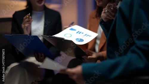 Three women are sitting together and looking at some papers. They are discussing something important. Scene is serious and focused