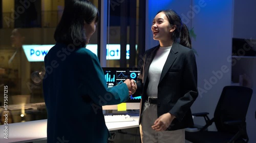 A woman stands in front of a computer monitor with Powerhouse Pilots written on the wall behind her