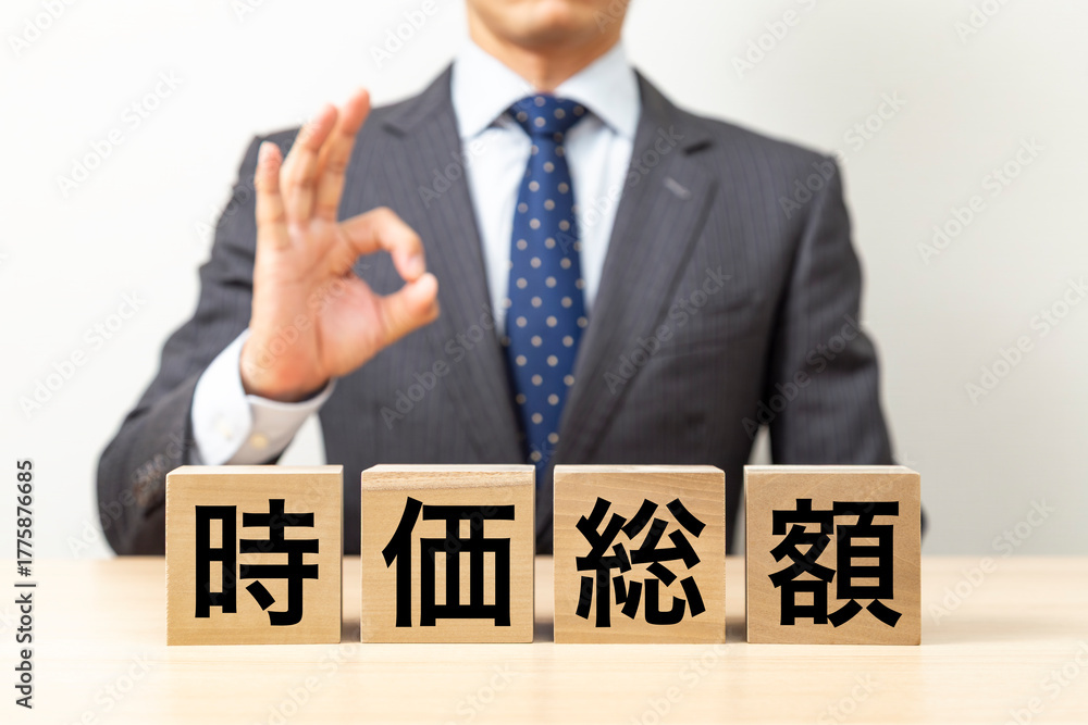 Obraz premium 「時価総額」と書かれたブロックとOKポーズをするビジネスマン