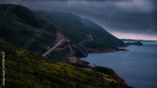 Foto Moody coastal view of the Cabot Trail in Cape Breton, Nova Scotia, with a winding road along steep forested cliffs above the Gulf of St