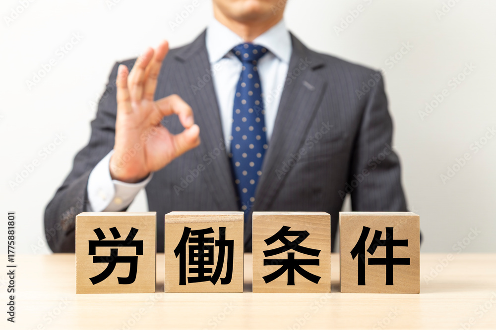 Obraz premium 「労働条件」と書かれたブロックとOKポーズをするビジネスマン