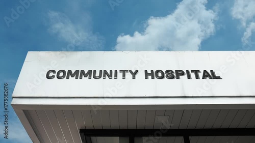 Community Hospital word sign prominently displayed on the accessible institutional facade beneath a clear blue sky, signifying a non-profit medical center dedicated to serving the immediate local