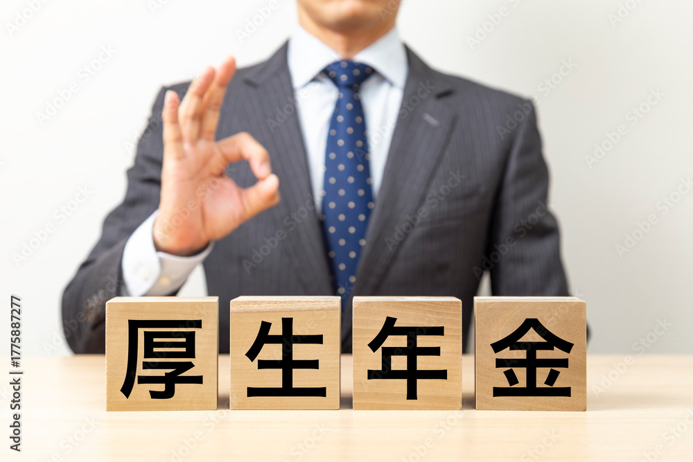 Obraz premium 「厚生年金」と書かれたブロックとOKポーズをするビジネスマン