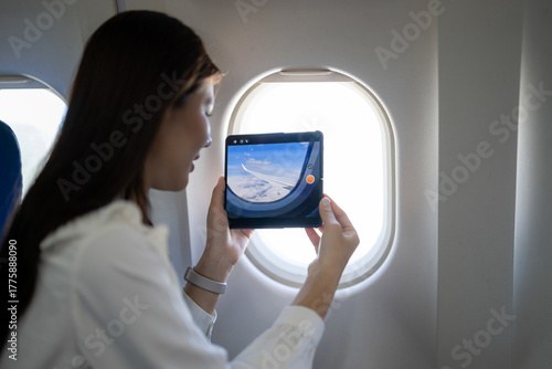 Fotografi Woman recording airplane wing with foldable phone during flight