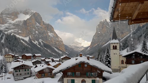 scenic winter landscape showing a tiny hamlet nestled in a range of majestic pale mountains completely covered in