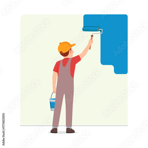 Man painting wall blue using paint roller wearing cap and overall from behind view