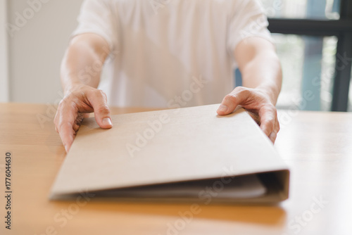 handing over a brown folder across the desk, concept for document delivery, business agreement, contract signing professional office communication.