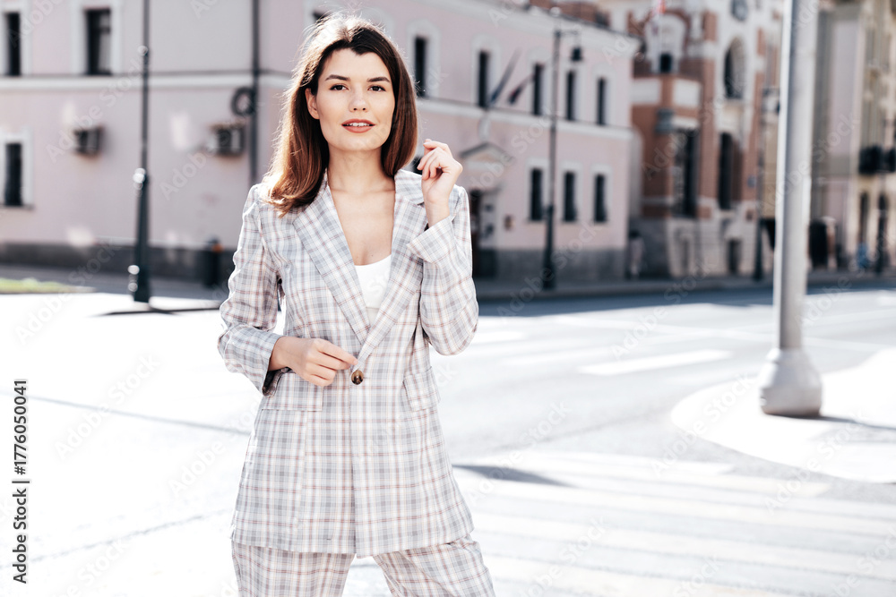 Fototapeta premium Portrait of young beautiful brunette woman wearing nice trendy plaid suit jacket. Sexy smiling model posing in the street at sunny day. Fashionable female outdoors. Cheerful and happy.