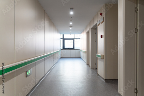  clean hospital corridor with green handrails, doors, and bright lights