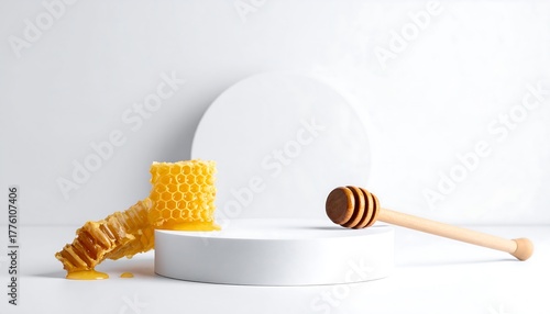 A honeycomb section drips golden liquid onto a platform beside a honey dipper, against a white backdrop