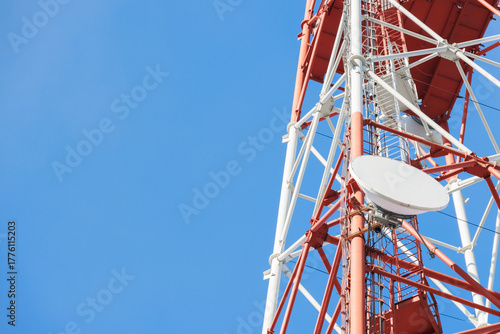 A close-up view of a telecommunication tower with a satellite dish, set against a bright blue sky, symbolizing modern communication technology.