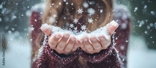 Female hands holding sparkling snowflakes on a white winter background. Cozy winter and Christmas concept.