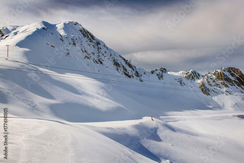 view on freshly snow-covered ski slope under white cloud in the sky and snowy...