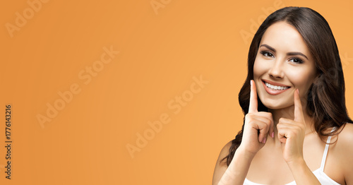 Image - happy cute woman point  hands fingers bright toothy smile. Optimistic girl show white tooth, isolated warm orange background with free ad text space. Dental health care ad concept. Wide banner