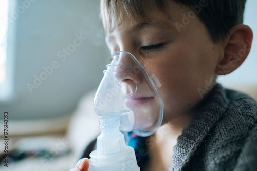 Child using inhaler for cough and cold treatment indoors
