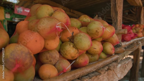 Close-up of mangoes in fruit nets on makeshift stall. Slow motion.